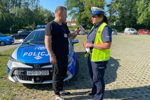 Policjantka przy radiowozie udziela wywiadu radiowego.