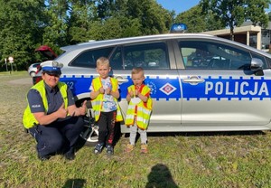 Policjantka z ruchu drogowego pozuje przy radiowozie z dwójką chłopców.