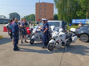 Policjanci z drogówki stoją przy motocyklach, rozmawiają z uczestnikami pikniku