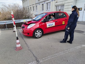 W samochodzie nalezącym do WORD za kierownicą siedzi młody meżczyzna. Obok samochodu stoi policjantka.