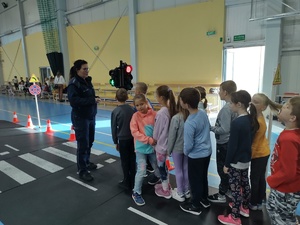 Policjantka omawia dzieciom zasady korzystania z przejścia dla pieszych z sygnalizacją świetlną